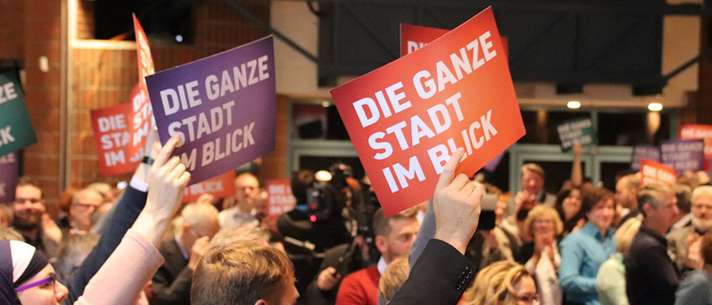 Foto: "Die ganze Stadt im Blick"-Schilder werden in die Luft gehalten