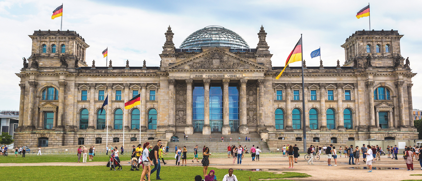 Foto: Menschen spazieren vor dem Reichstagsgebäude in Berlin